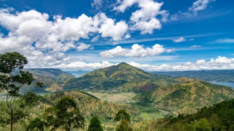 Spot panorama Danau Toba yang estetik dengan hamparan danau dan perbukitan hijau di Sumatra Utara