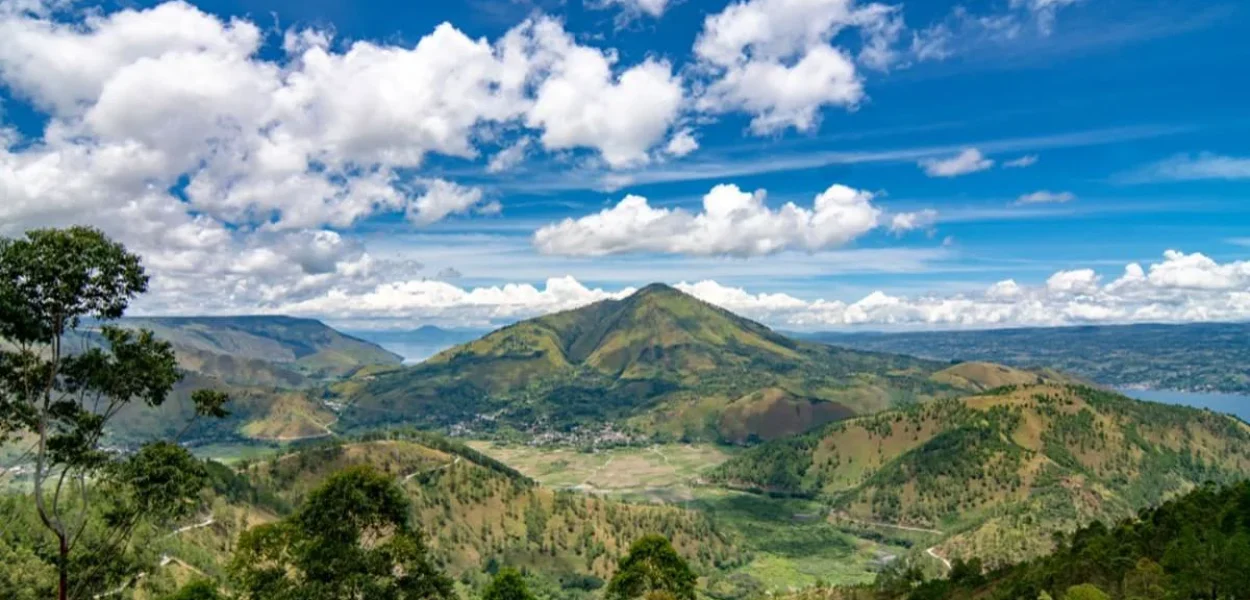 Spot panorama Danau Toba yang estetik dengan hamparan danau dan perbukitan hijau di Sumatra Utara